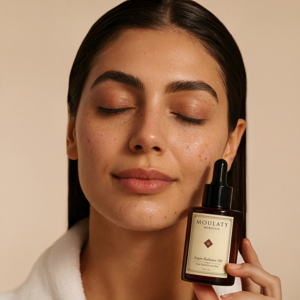 Woman with glowing skin holding Moulaty Argan Radiance Oil skincare product
