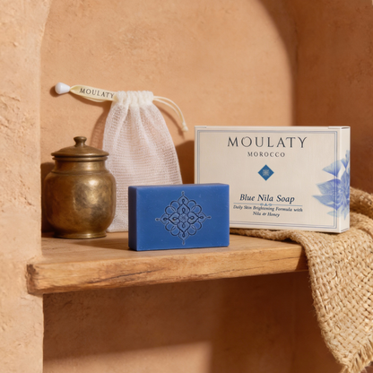 Blue Nila soap bar with intricate design, packaging, and Moroccan decor on a wooden shelf