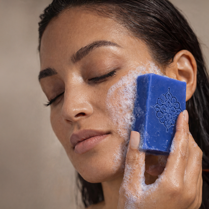 Woman cleansing face with blue Nila soap bar, Moroccan skincare, rich lather, close-up