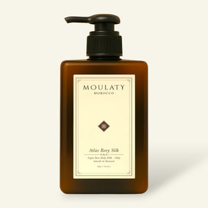 Amber pump bottle of Atlas Rosy Silk argan rose body milk against a beige background.