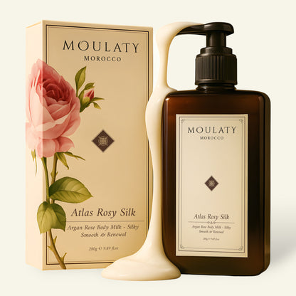 Argan rose body milk bottle with pump, creamy lotion flowing, floral packaging beside it