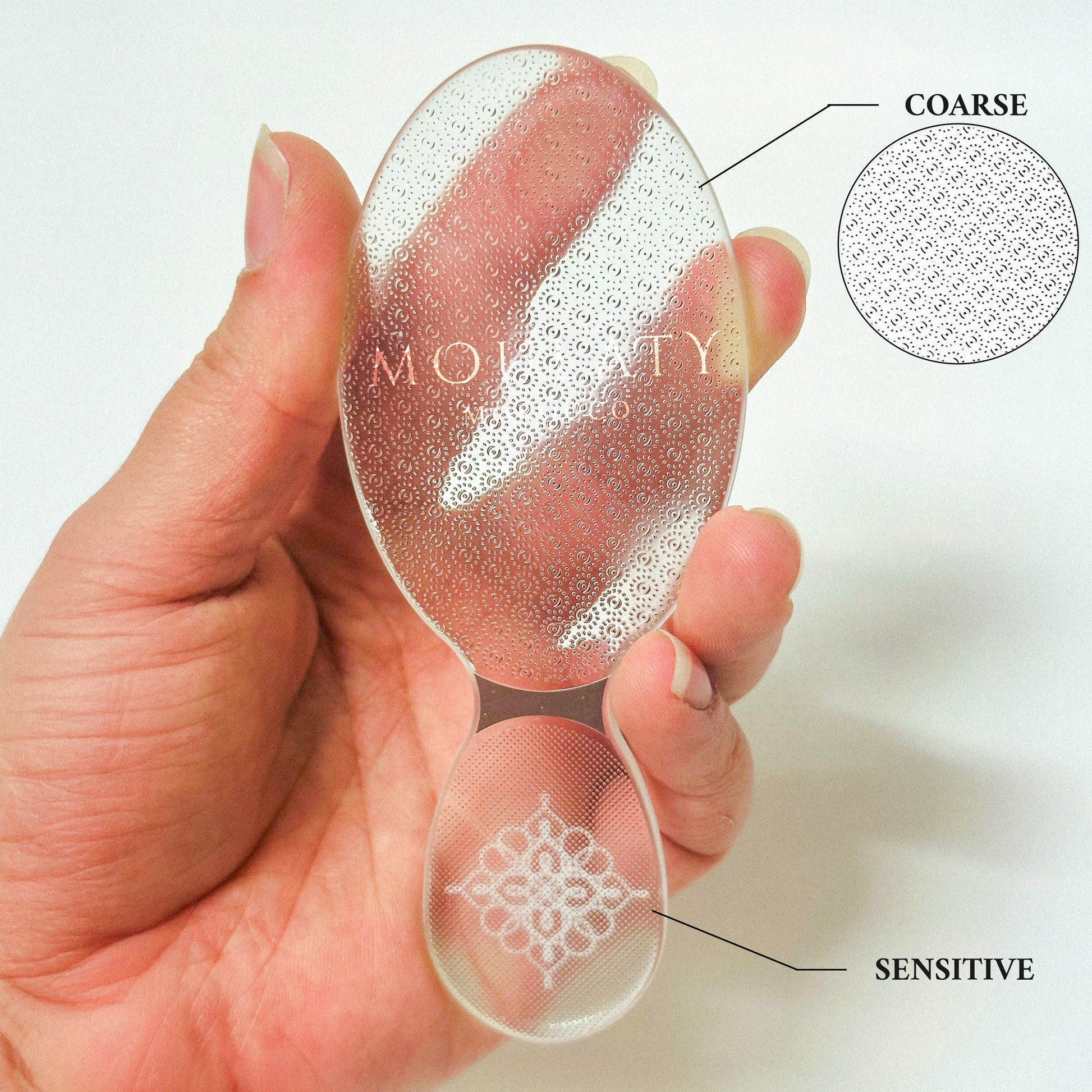 Hand holding a dual-sided glass foot file with coarse and sensitive textured surfaces for exfoliating feet.