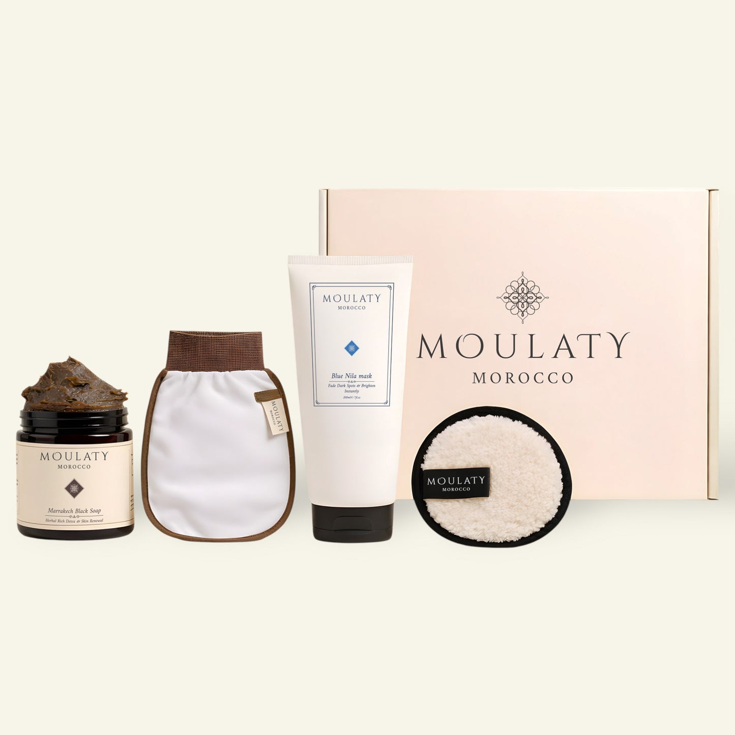 Moroccan skincare set with black soap, Blue Nila mask, exfoliating mitt, pad, and gift box.