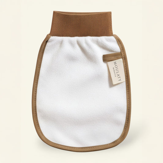 Exfoliating Moroccan kessa glove with brown trim for hammam skincare rituals on neutral background