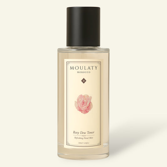 Clear bottle of Moulaty Rosy Dew Toner with rose label and black cap on beige background