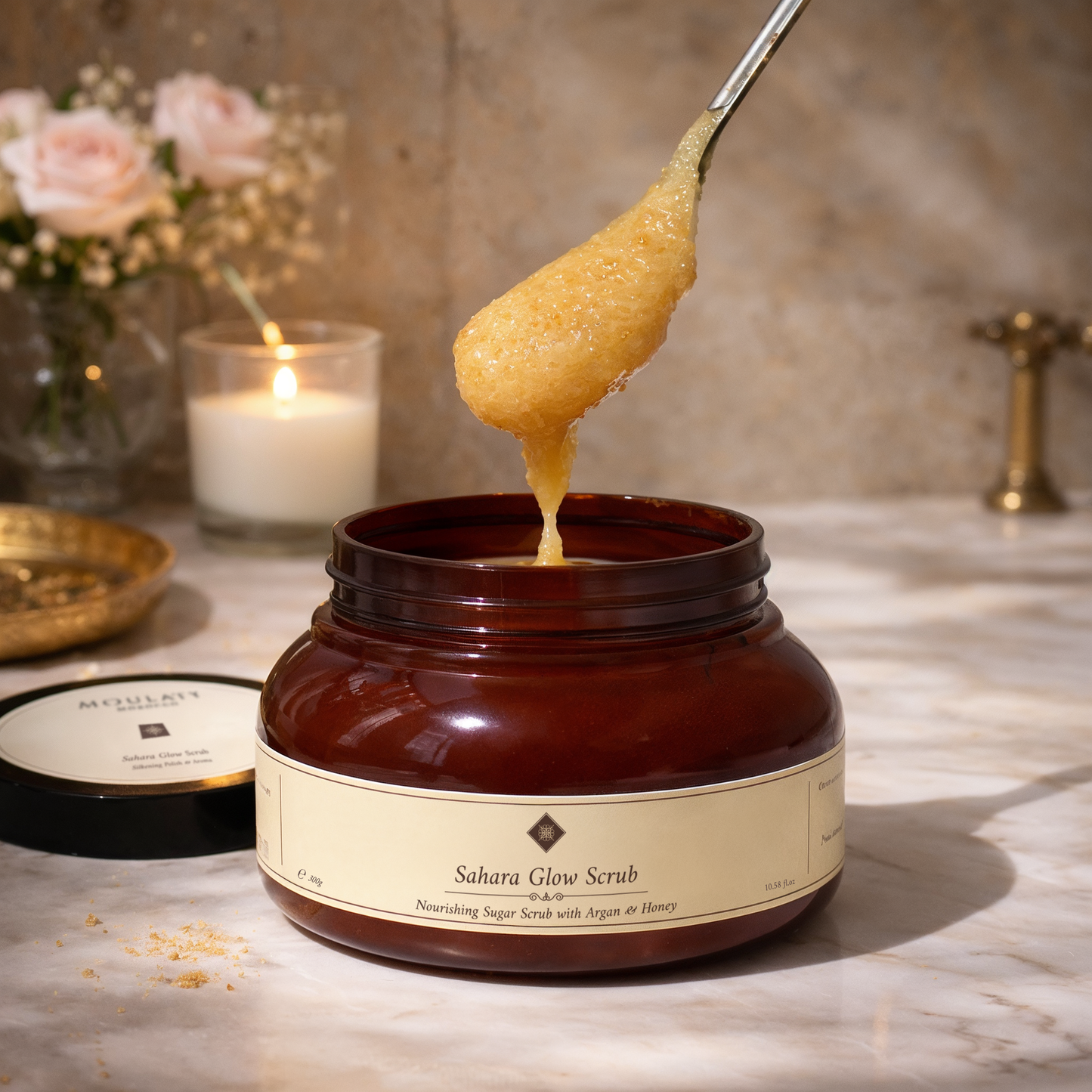Open jar of Sahara Glow Scrub sugar exfoliant with argan and honey on marble counter