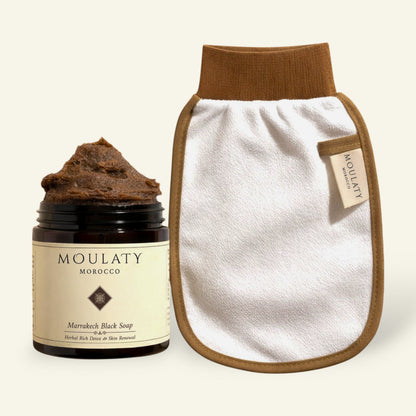 Moroccan black soap jar with exfoliating glove for hammam skincare and gentle cleansing.
