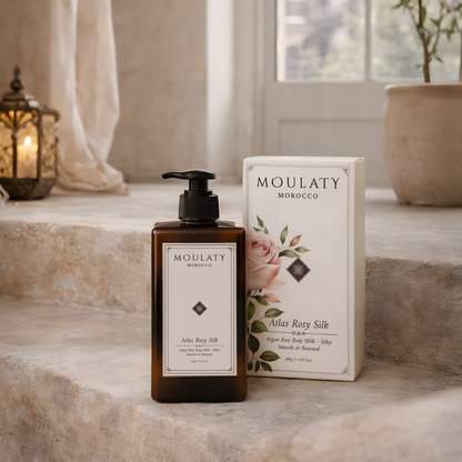 Atlas Rosy Silk argan rose body milk bottle and box on a stone surface with soft natural lighting